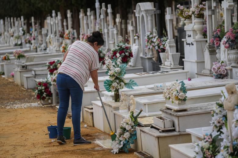 Una mujer limpia la tumba de un familiar en el cementerio de San Fernando, Sevilla