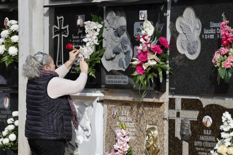 Una mujer coloca flores en un nicho del cementerio de Catarroja, Valencia