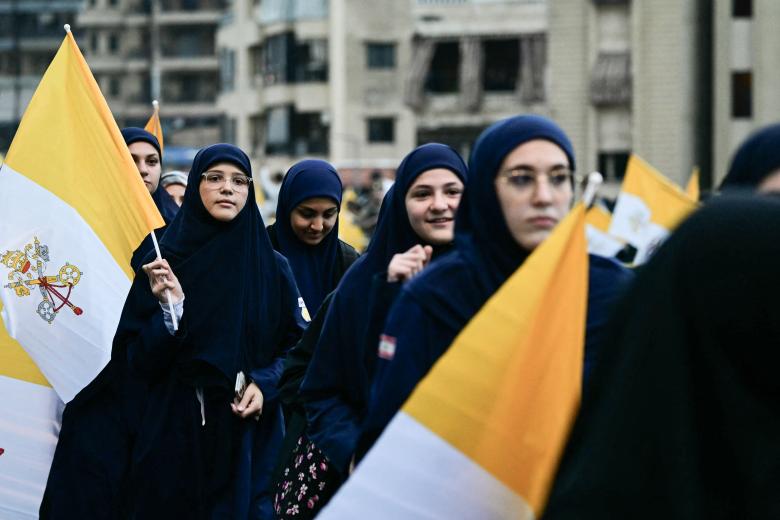 Imam Al-Mahdi scouts hold portraits of Pope Leo XIV as they wait for his arrival in Beirut's southern suburbs, a packed residential area known as Dahiyeh, which is also a Hezbollah bastion, on November 30, 2025. Pope Leo XIV arrived in Lebanon with a message of peace for the crisis-hit nation, still reeling from a war between Israel and Hezbollah and the conflict's lingering aftereffects. (Photo by Giuseppe CACACE / AFP)