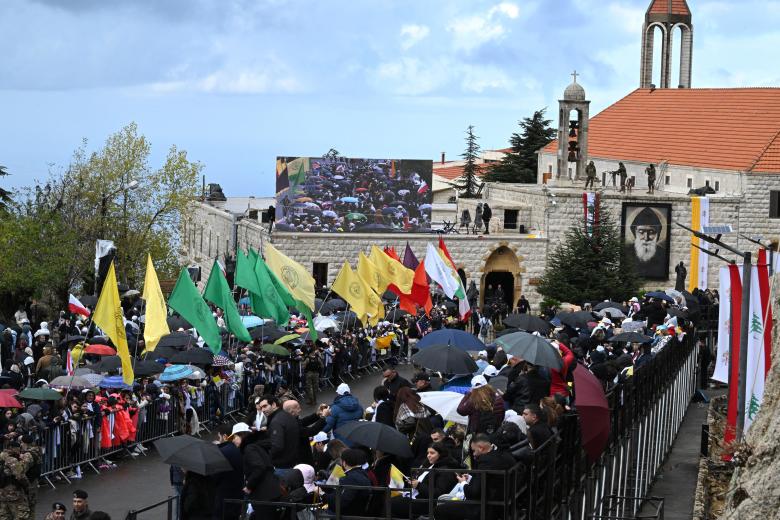 Lebanese Muslim women hold Vatican flags as they wait for the arrival of Pope Leo XIV in Beirut's southern suburbs, a packed residential area known as Dahiyeh, which is also a Hezbollah bastion, on November 30, 2025. Pope Leo XIV arrived in Lebanon with a message of peace for the crisis-hit nation, still reeling from a war between Israel and Hezbollah and the conflict's lingering aftereffects. (Photo by Giuseppe CACACE / AFP)