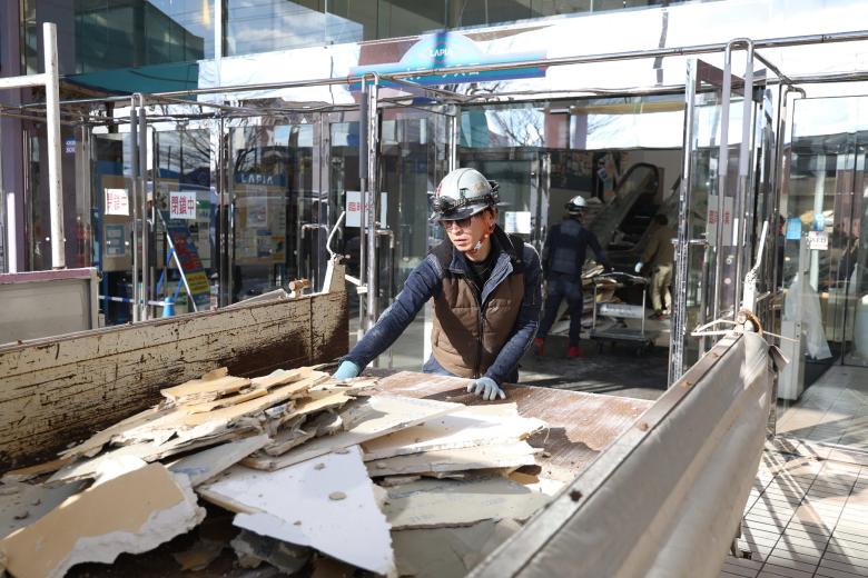 A worker clears debris at a shopping center damaged by the earthquake in Hachinohe City, Aomori Prefecture on December 9, 2025. (Photo by JIJI Press / AFP) / Japan OUT / JAPAN OUT / JAPAN OUT