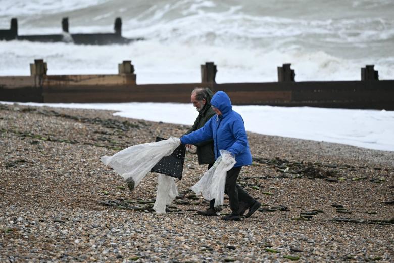 Los voluntarios trabajan para recoger plátanos y bananas de la playa después de que los contenedores que se cayeron del carguero Baltic Klipper llegaran a la costa de Inglaterra. La búsqueda de los contenedores desaparecidos continúa, con la guardia costera desplegando un helicóptero y una avioneta.
