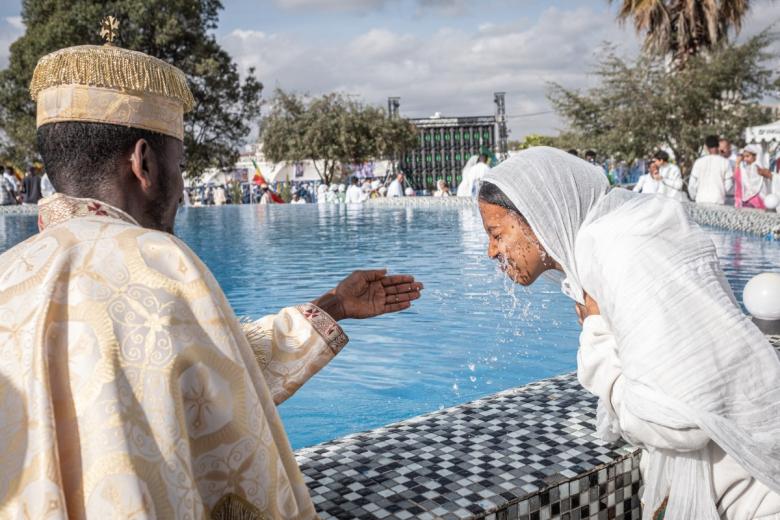 Un sacerdote ortodoxo rocía agua bendita en el rostro de un joven adorador cerca de la piscina ceremonial al final de la liturgia de Timkat, recreando el bautismo de Jesús, en Jan Meda, Adís Abeba