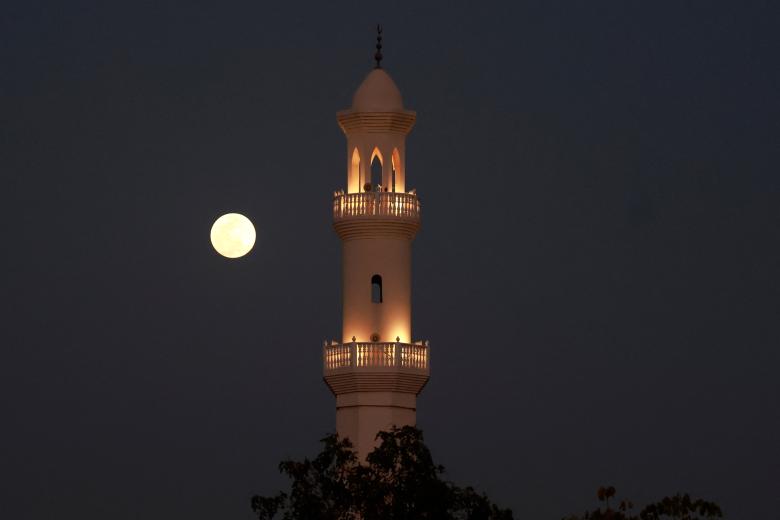 La luna llena sale detrás de una mezquita en Doha