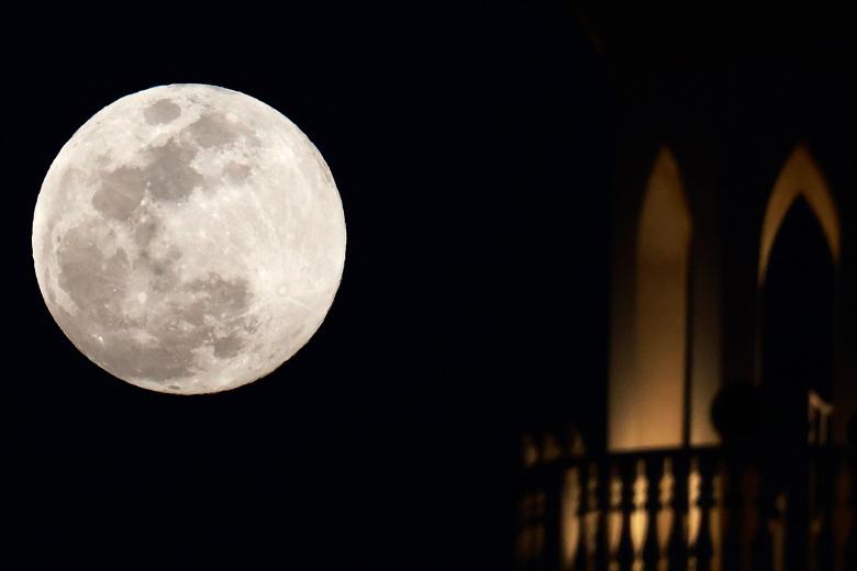 La luna llena sale detrás de una mezquita en Doha