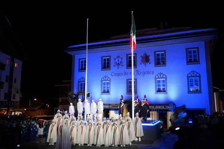 La bandera italiana se iza mientras un coro canta el himno nacional durante la ceremonia de apertura de los Juegos Olímpicos de Invierno