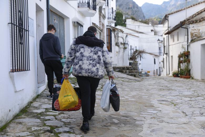 GRAZALEMA (CÁDIZ), 16/02/2026.- Un hombre porta enseres en una calle de Grazalema este lunes. Un primer grupo de vecinos desalojados hace 11 días por el temporal en Grazalema (Cádiz) ha podido volver a sus hogares a partir de las 16:05 horas de este lunes, cuando la Guardia Civil ha permitido el acceso a una treintena de vehículos al municipio. EFE/ Jorge Zapata