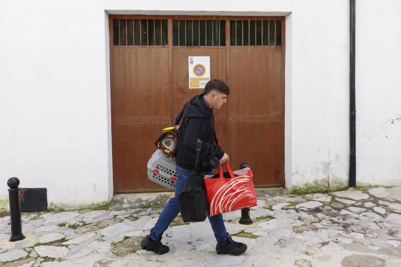 GRAZALEMA (CÁDIZ), 16/02/2026.- Un hombre porta enseres en una calle de Grazalema este lunes. Un primer grupo de vecinos desalojados hace 11 días por el temporal en Grazalema (Cádiz) ha podido volver a sus hogares a partir de las 16:05 horas de este lunes, cuando la Guardia Civil ha permitido el acceso a una treintena de vehículos al municipio. EFE/ Jorge Zapata