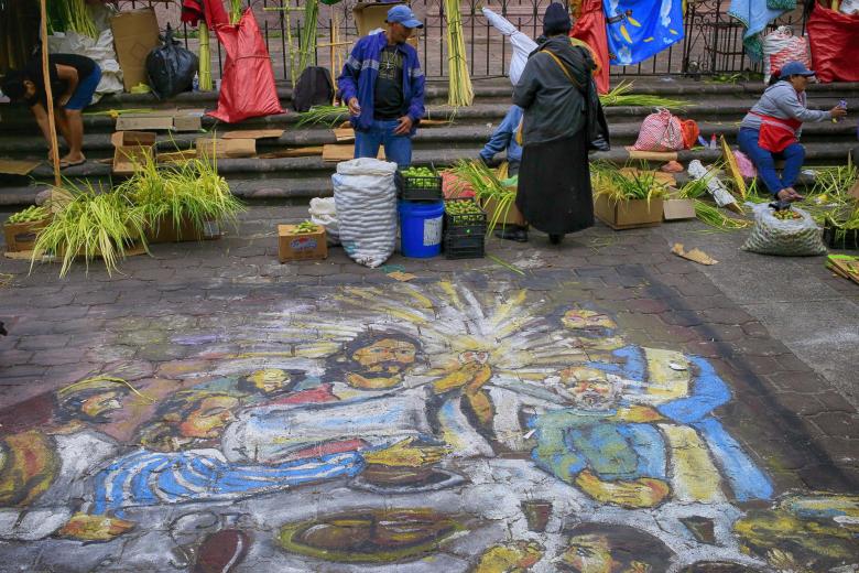 Personas venden ramos de palma antes de la celebración del Domingo de Ramos, delante de una pintura en el suelo de la Última Cena, en Tegucigalpa, Honduras