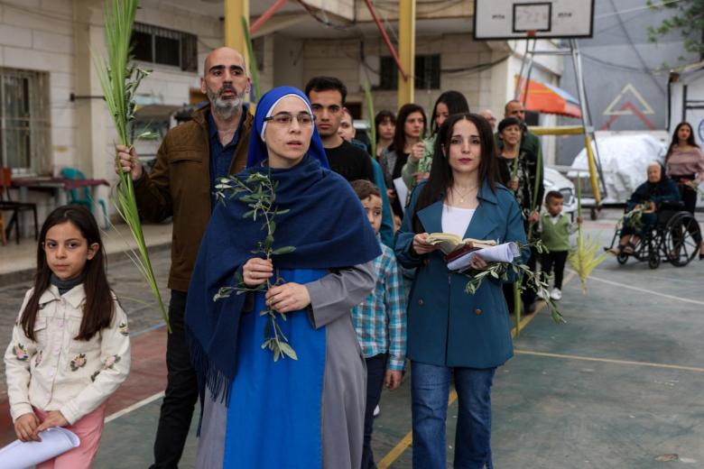 Una monja y fieles asisten a la procesión durante la misa del Domingo de Ramos en la Iglesia Católica Romana de la Sagrada Familia en la ciudad de Gaza.