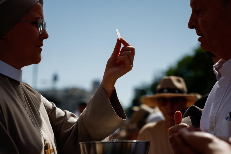 Una monja da la comunión en la Plaza de Cibeles durante la misa del Corpus Christi oficiada por papa León XIV este domingo en Madrid