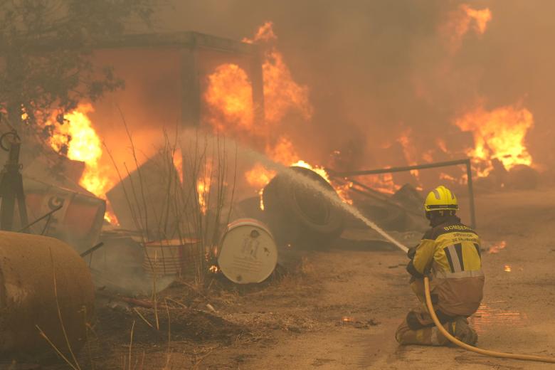 Un bombero riega neumáticos y barriles en llamas en la provincia de Ávila