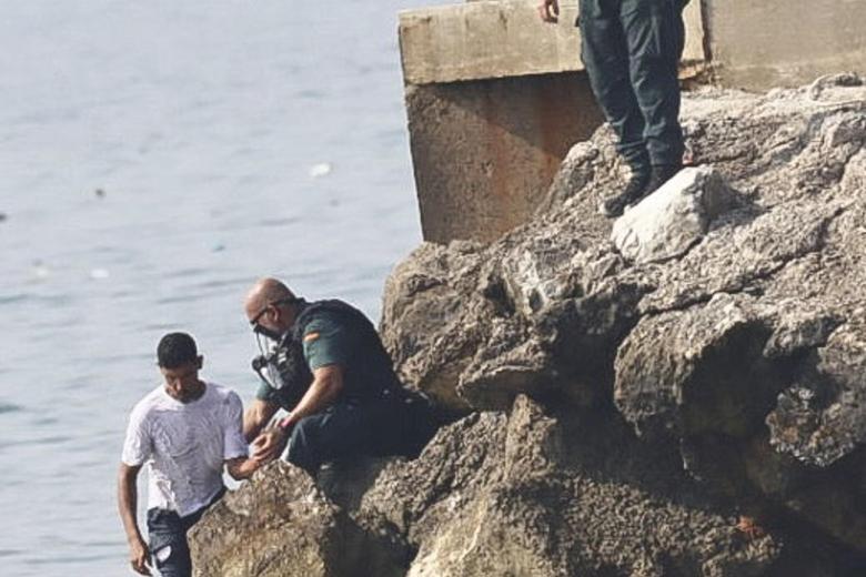 A unos 500 metros de la frontera permanecían desplegados una docena de agentes marroquíes en un control de acceso, aunque la marea humana seguía llegando de forma ininterrumpida desde distintos puntos de los alrededores. España y Marruecos han acordado la entrega  de quienes han entrado ilegalmente.