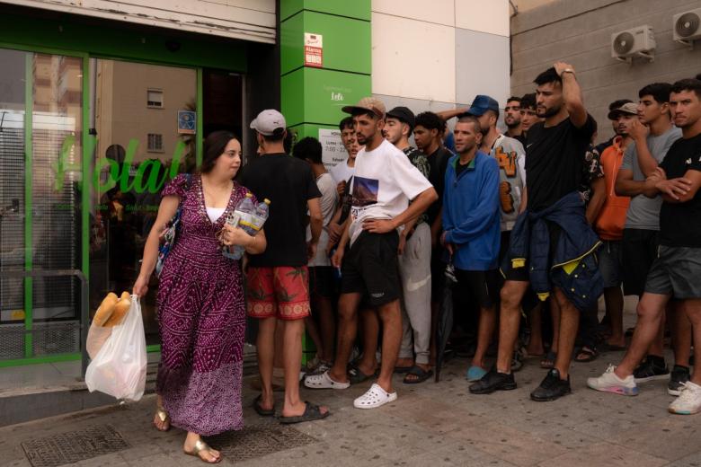 Una joven sale del supermercado mientras varios jóvenes la miran.