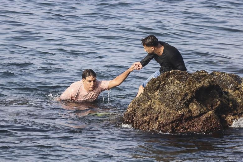 Un marroquí ayudando a otro a salir del agua para ingresar en Ceuta