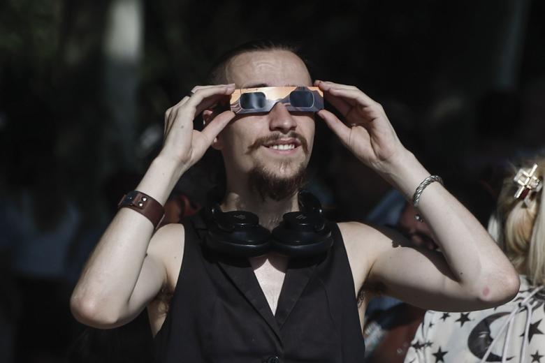 Un hombre se prueba unas gafas mientras espera el eclipse solar, este miércoles en el Templo de Debod, en Madrid