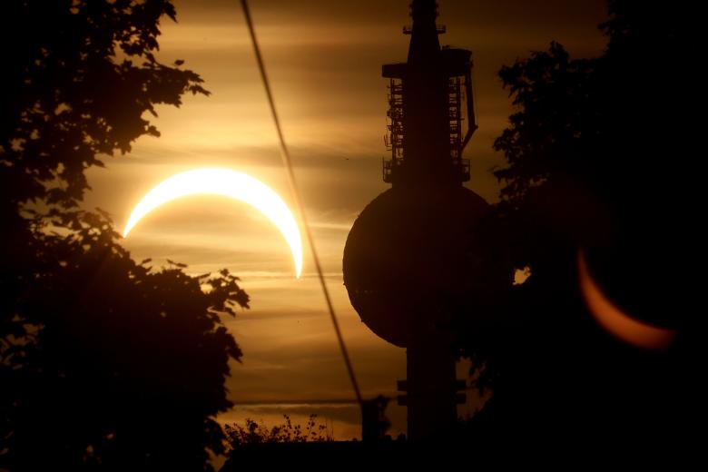Se observa una parte del Sol oculta por la Luna durante un eclipse solar parcial detrás de la torre de televisión de Berlín, Alemania.