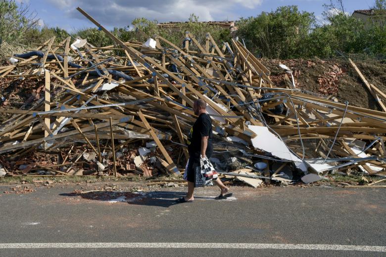 Un hombre camina junto a los escombros de un tejado dañado tras un tornado en Pomas, en el suroeste de Francia.