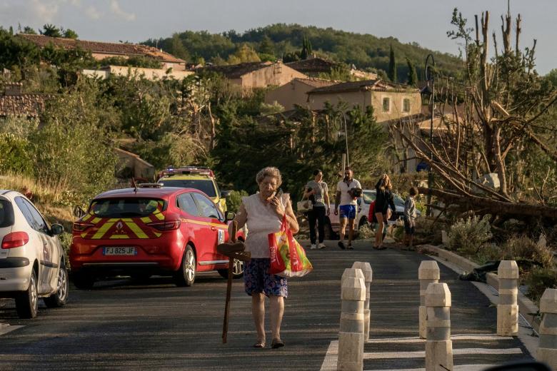 Unos peatones pasan junto a un árbol derribado y cerca de viviendas dañadas después de que un tornado azotara Pomas, en el suroeste de Francia.