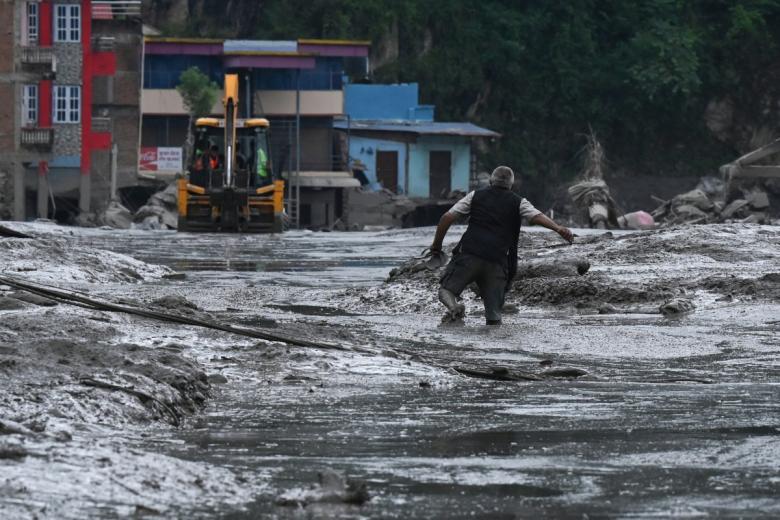 Un residente camina por una calle cubierta de barro tras unas inundaciones repentinas y un deslizamiento de tierra en Devighat, en el distrito nepalí de Nuwakot