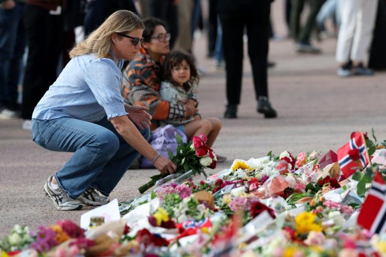 Una mujer deposita una flor en homenaje al Rey Harald V de Noruega, fallecido, en la plaza del Palacio Real de Oslo el 28 de agosto de 2026