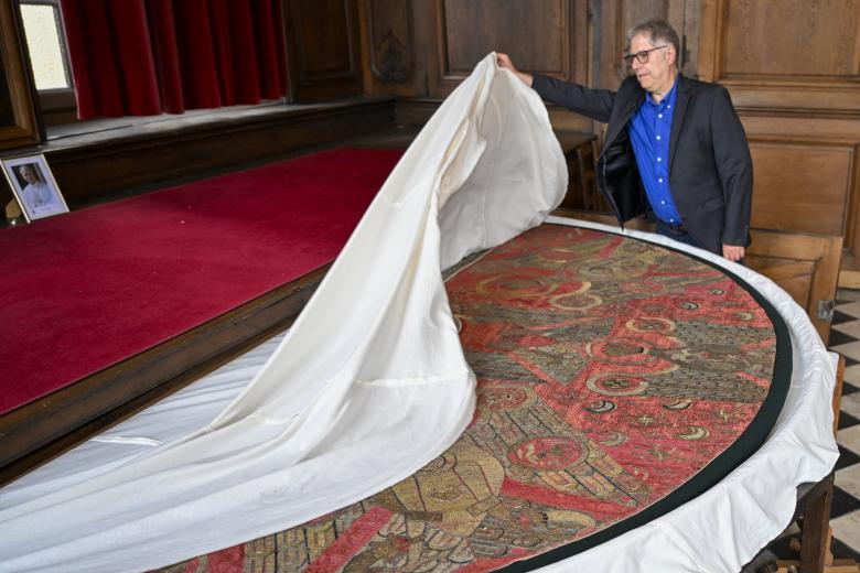 Chairman of the Metz Cathedral Trust Philippe Hiegel unveils the cope of Charlemagne, a liturgical cope made of red silk woven with gold and silver, and the coronation cloak of Emperor Frederick II of Hohenstaufen, in the crypt of Saint-Etienne Cathedral in Metz, eastern France, on September 3, 2026. Leo XIV's stop in Metz on September 28 will mark the first papal visit to the city since Pope John Paul II in 1988, and will close out his four-day apostolic journey to France that also esi:includes Paris and Lourdes. (Photo by Jean-Christophe VERHAEGEN / AFP)