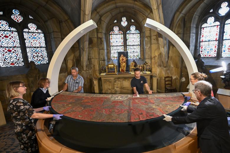 Chairman of the Metz Cathedral Trust Philippe Hiegel unveils the cope of Charlemagne, a liturgical cope made of red silk woven with gold and silver, and the coronation cloak of Emperor Frederick II of Hohenstaufen, in the crypt of Saint-Etienne Cathedral in Metz, eastern France, on September 3, 2026. Leo XIV's stop in Metz on September 28 will mark the first papal visit to the city since Pope John Paul II in 1988, and will close out his four-day apostolic journey to France that also esi:includes Paris and Lourdes. (Photo by Jean-Christophe VERHAEGEN / AFP)
