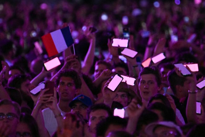 Personas sostienen en alto sus teléfonos móviles iluminados mientras aguardan a que el Papa León dirija la vigilia