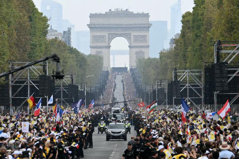 León XIV saluda a la multitud desde el «Papamóvil» mientras recorre la avenida de los Campos Elíseos, con el Arco del Triunfo al fondo, de camino a la plaza de la Concordia, en el centro de París