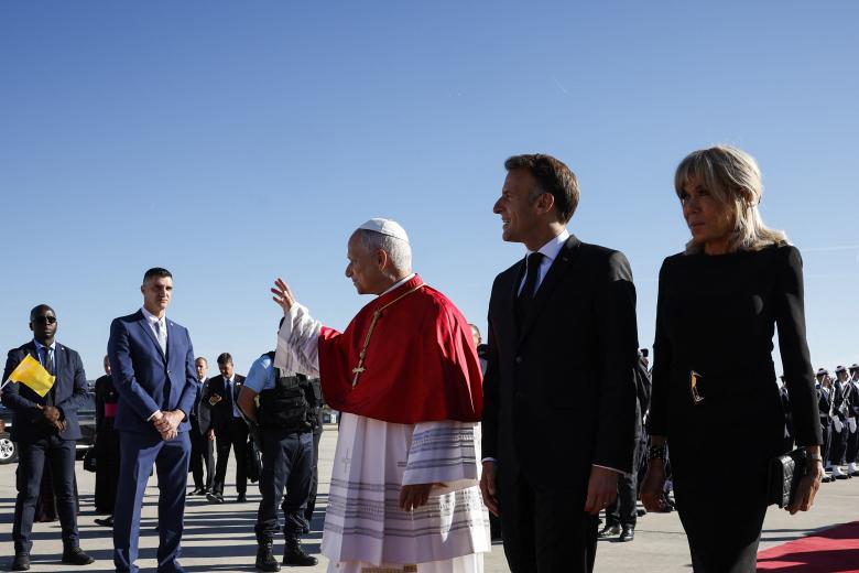 León XIV (izquierda), junto al presidente francés Emmanuel Macron (centro) y su esposa Brigitte Macron (derecha), asiste a una ceremonia de bienvenida tras bajar del avión a su llegada al aeropuerto de Orly