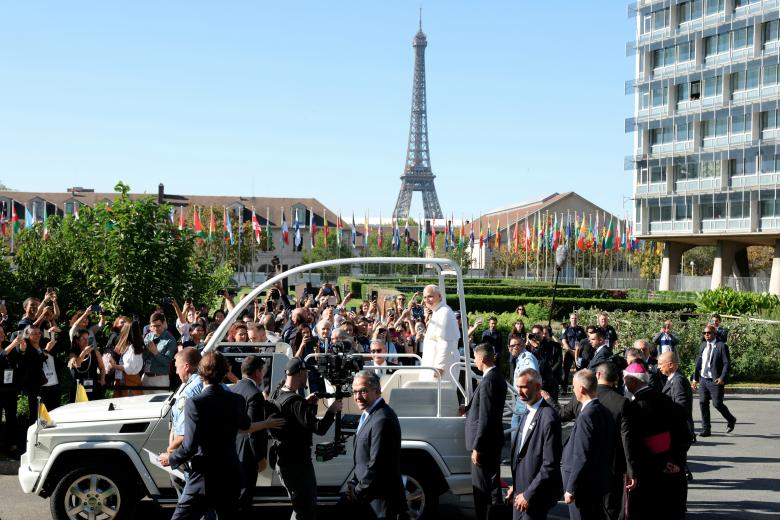El papa León XIV saluda a la multitud al iniciar su recorrido por las calles de París en el «Papamóvil», frente a la sede de la UNESCO, con la Torre Eiffel al fondo, el 25 de septiembre de 2026, en el marco de su visita de cuatro días a Francia. (Foto de Thomas SAMSON / AFP)