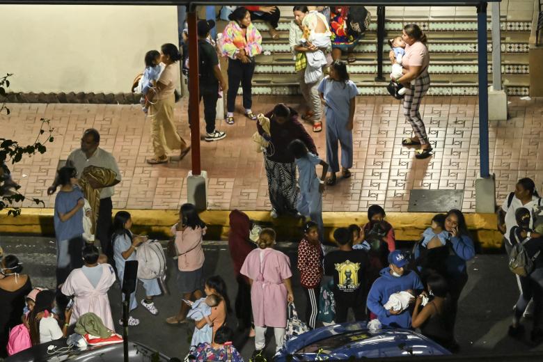 Personas que llevan bebés en brazos evacúan el Hospital Infantil tras percibirse una réplica de seis grados.