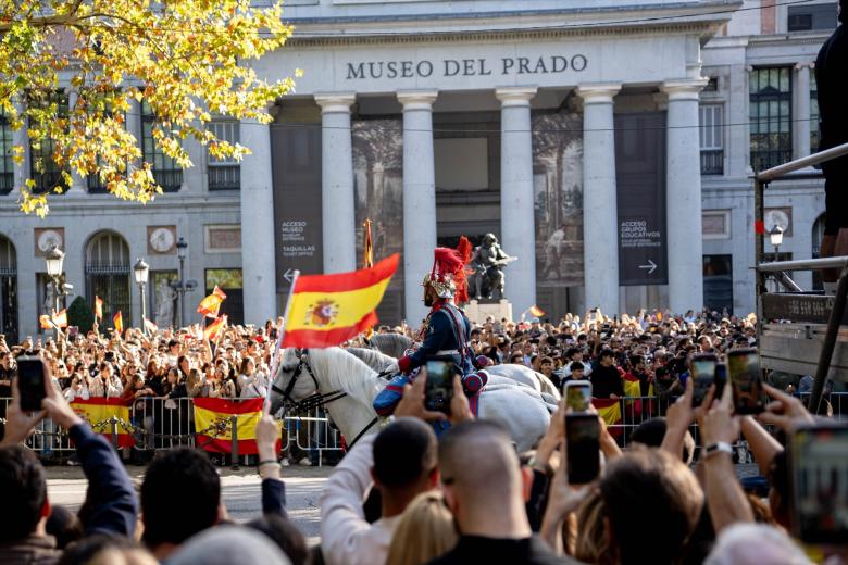 Varias personas disfrutan del desfile durante el acto solemne de homenaje a la bandera nacional y desfile militar por el 12 de octubre, Día de la Hispanidad, en la Plaza de Cánovas del Castillo, a 12 de octubre de 2026, en Madrid (España). Los actos comienzan con el izado de bandera y van seguidos del homenaje a los que dieron la vida por el país. Posteriormente, comienzan los desfiles militares aéreos y terrestres. Alrededor de 4.400 integrantes de las Fuerzas Armadas, las Fuerzas y Cuerpos de Seguridad y distintas instituciones públicas civiles participan este año en el desfile presidido por los Reyes. El desfile aéreo ha contado con 50 aeronaves de caza, enseñanza y transporte, además de alrededor de 30 helicópteros. Por tierra han participado unos 144 vehículos y 39 motocicletas, además de unos 300 caballos y cinco perros pertenecientes a distintas unidades.

Gabriel Luengas / Europa Press
12/10/2026