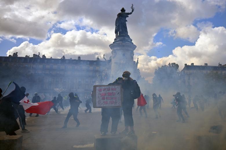 Varios manifestantes tratan de escapar del gas lacrimógeno lanzado por las fuerzas del orden en París