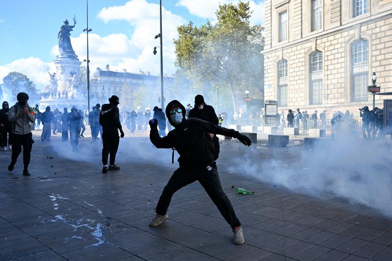 Un manifestante, aparentemente joven, lanza algo contra los agentes antidisturbios en París