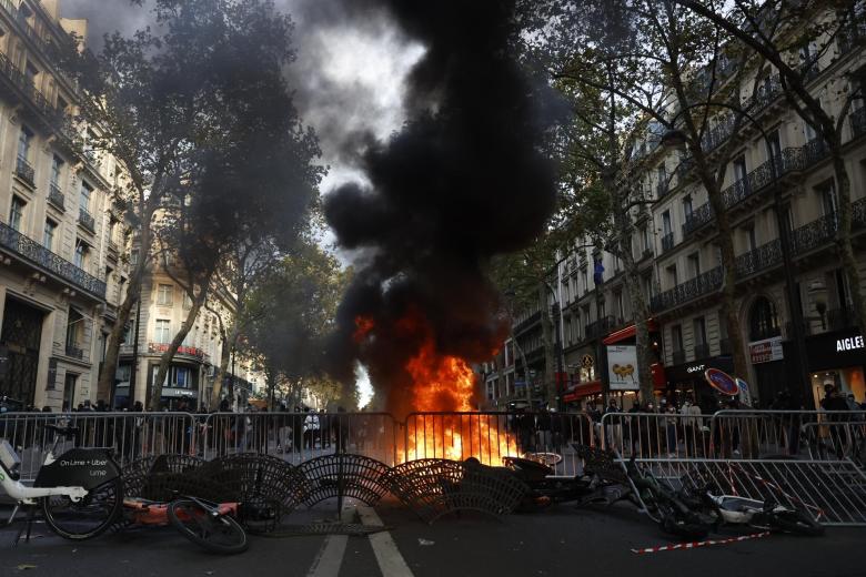 Paris (France), 17/10/2026.- A man rides a bicycle past a fire in the street during a demonstration against rising living costs and cuts to public services in Paris, France, 17 October 2026. The nationwide mobilization brought together Yellow Vest (Gilets Jaunes) activists, high school and university students, trade unions and other groups protesting rising living costs, fuel prices and deteriorating public services, while demanding improvements in education and school conditions. (Protestas, Francia) EFE/EPA/MOHAMMED BADRA