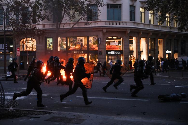 A protestor with a gas mask holds a French flag in front of a fire at the Boulevard des Capucines during a demonstration to protest against the "high cost of living", in Paris on October 17, 2026 as part of a nationwide call for mobilisation bringing together various groups expressing their anger: former "Yellow Vests", secondary school and university students, climate activists and even farmers. After weeks of student protests, France faces broader, nationwide demonstrations on October 17, 2026 over the cost of living, setting up a potentially fraught six months heading into a presidential election. A police source told AFP that authorities estimated nearly 200,000 people could take part, with 40,000 in Paris. (Photo by Kiran RIDLEY / AFP)