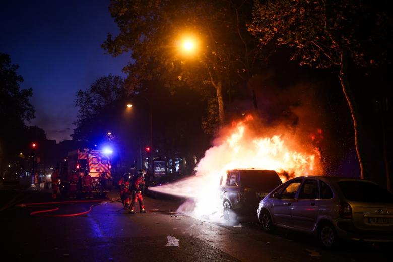 A demonstrator holds a placards which reads as "Their power stays standing as long as our anger stays seated" while standing among tear gas behind a barricade they built with street pavement during ongoing protest action against the "high cost of living", in Lyon, southeastern France, on October 17, 2026 as part of a nationwide call for mobilisation bringing together various groups expressing their anger: former "Yellow Vests", secondary school and university students, climate activists and even farmers. After weeks of student protests, France faces broader, nationwide demonstrations on October 17, 2026 over the cost of living, setting up a potentially fraught six months heading into a presidential election. A police source told AFP that authorities estimated nearly 200,000 people could take part, with 40,000 in Paris. (Photo by JEFF PACHOUD / AFP)