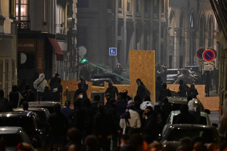 Firefighters extinguish a burning car at the Boulevard des Capucines during a demonstration to protest against the "high cost of living", in Paris on October 17, 2026 as part of a nationwide call for mobilisation bringing together various groups expressing their anger: former "Yellow Vests", secondary school and university students, climate activists and even farmers. After weeks of student protests, France faces broader, nationwide demonstrations on October 17, 2026 over the cost of living, setting up a potentially fraught six months heading into a presidential election. A police source told AFP that authorities estimated nearly 200,000 people could take part, with 40,000 in Paris. (Photo by Kiran RIDLEY / AFP)