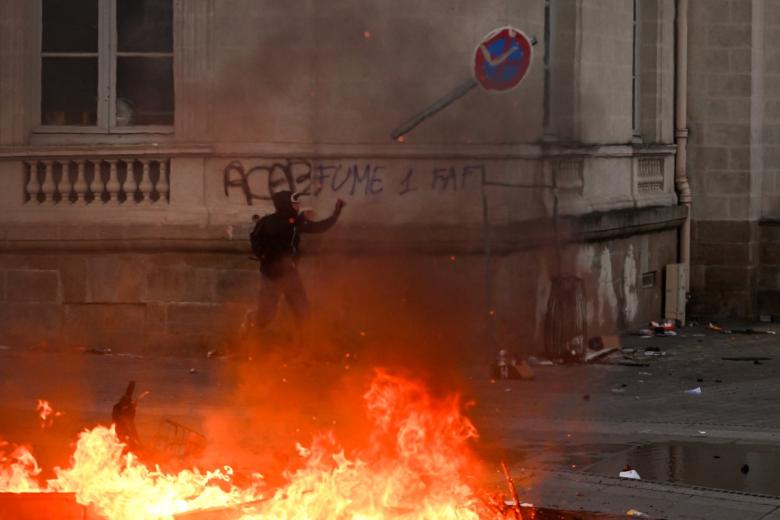 A protester feeds a fire with a material along the Canal Saint-Martin during ongoing protest action against the "high cost of living", in Paris on October 17, 2026 as part of a nationwide call for mobilisation bringing together various groups expressing their anger: former "Yellow Vests", secondary school and university students, climate activists and even farmers. After weeks of student protests, France faces broader, nationwide demonstrations on October 17, 2026 over the cost of living, setting up a potentially fraught six months heading into a presidential election. A police source told AFP that authorities estimated nearly 200,000 people could take part, with 40,000 in Paris. (Photo by DIMITAR DILKOFF / AFP)