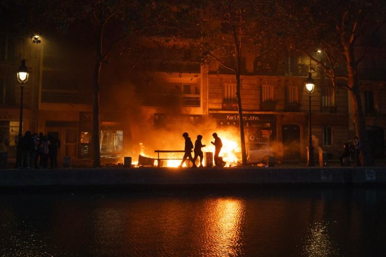 A protester throws a road pillar next to a fire during a demonstration to protest against the "high cost of living", in Nantes, western France, on October 17, 2026 as part of a nationwide call for mobilisation bringing together various groups expressing their anger: former "Yellow Vest", secondary school and university students, climate activists and even farmers. After weeks of student protests, France faces broader, nationwide demonstrations on October 17, 2026 over the cost of living, setting up a potentially fraught six months heading into a presidential election. A police source told AFP that authorities estimated nearly 200,000 people could take part, with 40,000 in Paris. (Photo by Sebastien Salom-Gomis / AFP)