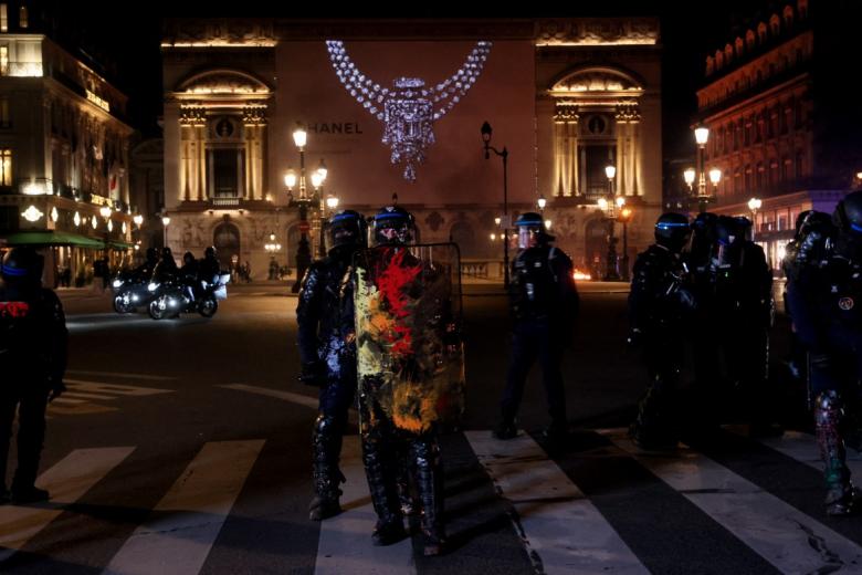 Protesters stand next to a fire along the Canal Saint-Martin during ongoing action against the "high cost of living", in Paris on October 17, 2026 as part of a nationwide call for mobilisation bringing together various groups expressing their anger: former "Yellow Vests", secondary school and university students, climate activists and even farmers. After weeks of student protests, France faces broader, nationwide demonstrations on October 17, 2026 over the cost of living, setting up a potentially fraught six months heading into a presidential election. A police source told AFP that authorities estimated nearly 200,000 people could take part, with 40,000 in Paris. (Photo by DIMITAR DILKOFF / AFP)