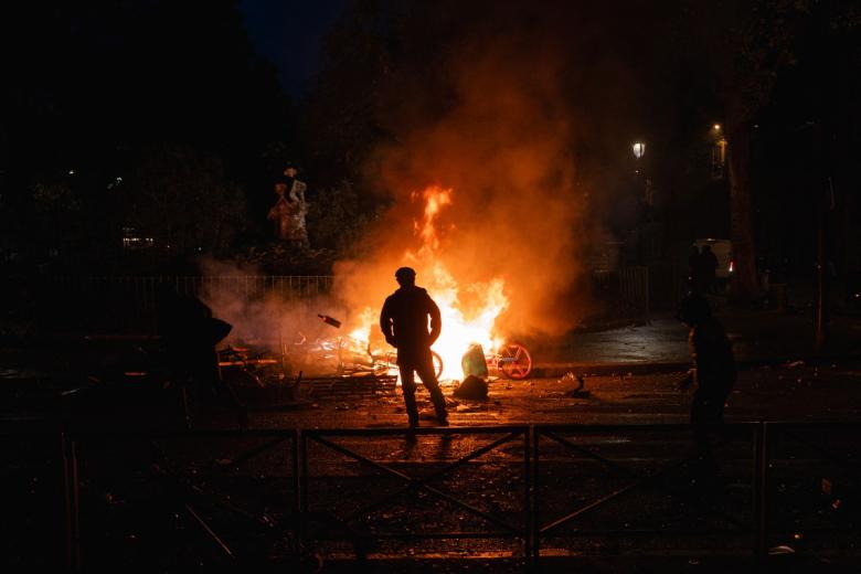 Protesters walk past a fire along the Canal Saint-Martin during ongoing action against the "high cost of living", in Paris on October 17, 2026 as part of a nationwide call for mobilisation bringing together various groups expressing their anger: former "Yellow Vests", secondary school and university students, climate activists and even farmers. After weeks of student protests, France faces broader, nationwide demonstrations on October 17, 2026 over the cost of living, setting up a potentially fraught six months heading into a presidential election. A police source told AFP that authorities estimated nearly 200,000 people could take part, with 40,000 in Paris. (Photo by DIMITAR DILKOFF / AFP)