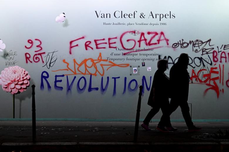A man walks past a broken woindow shop of Diesel following a demonstration against the "high cost of living", in Paris on October 17, 2026 as part of a nationwide call for mobilisation bringing together various groups expressing their anger: former "Yellow Vests", secondary school and university students, climate activists and even farmers. After weeks of student protests, France faces broader, nationwide demonstrations on October 17, 2026 over the cost of living, setting up a potentially fraught six months heading into a presidential election. A police source told AFP that authorities estimated nearly 200,000 people could take part, with 40,000 in Paris. (Photo by GEOFFROY VAN DER HASSELT / AFP)