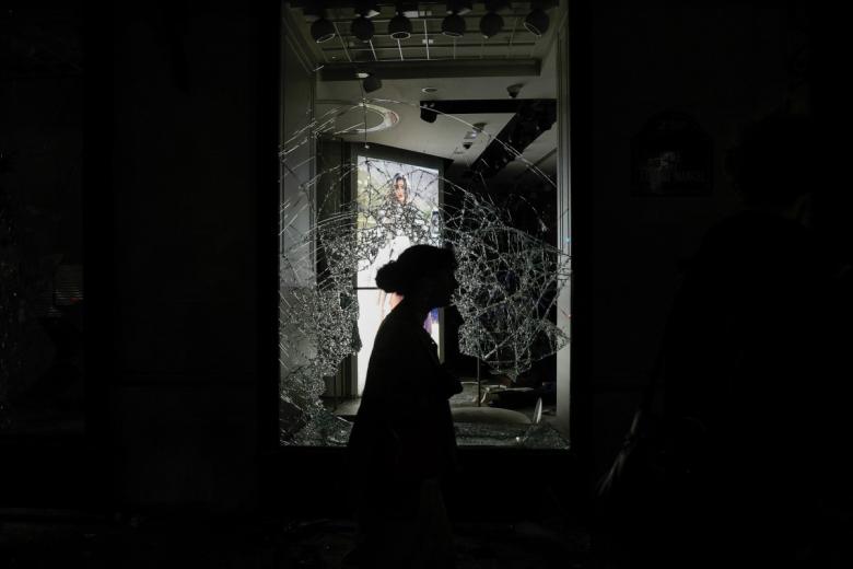 Pedestrians walk past a graffiti tags displayed on a store's security shutter following a rally called by "Yellow Vests" to protest against the "high cost of living", on the Boulevard des Capucines, in Paris on October 17, 2026 as part of a nationwide call for mobilisation bringing together various groups expressing their anger: former "Yellow Vest", secondary school and university students, climate activists and even farmers. After weeks of student protests, France faces broader, nationwide demonstrations on October 17, 2026 over the cost of living, setting up a potentially fraught six months heading into a presidential election. A police source told AFP that authorities estimated nearly 200,000 people could take part, with 40,000 in Paris. (Photo by Guillaume Saligot / AFP)
