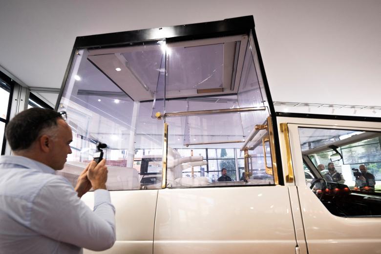 Visitors look at one of the historic papal vehicles on display at the Square Garden (Giardino Quadrato) during the press preview of the "A Century of Papamobile" exhibition, in the Vatican Museums, at the Vatican, on October 28, 2026. The exhibition "A century of the Popemobile", that presents eight historic vehicles mapping 100 years of papal mobility will open its doors on October 29, 2026. (Photo by TIZIANA FABI / AFP)