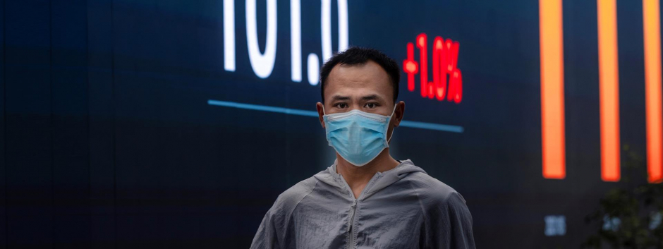 Un hombre camina frente a las pantallas de la bolsa de Shanghai, China