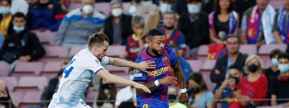El delantero holandés del FC Barcelona Memphis Depay (d) disputa el balón ante Tomasz Kedziora (i), defensa polaco del Dinamo de Kiev