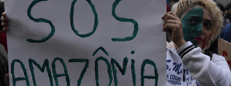 Una mujer muestra un cartel en el que pide ayuda para salvar la Amazonia brasileña