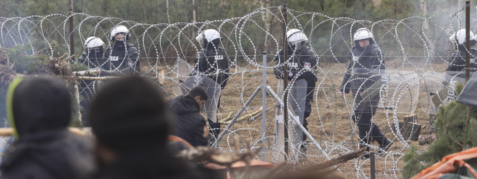 Soldados polacos observan desde su lado de la frontera a los refugiados y migrantes